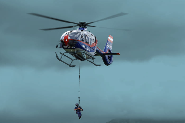 Fliegender Polizeihubschrauber mit einem Polizisten, der sich abseilt – steht für die maßgeschneiderten Versicherungen von RIANEVA für Angehörige des Bundesheeres, der Polizei und der Justizwache.